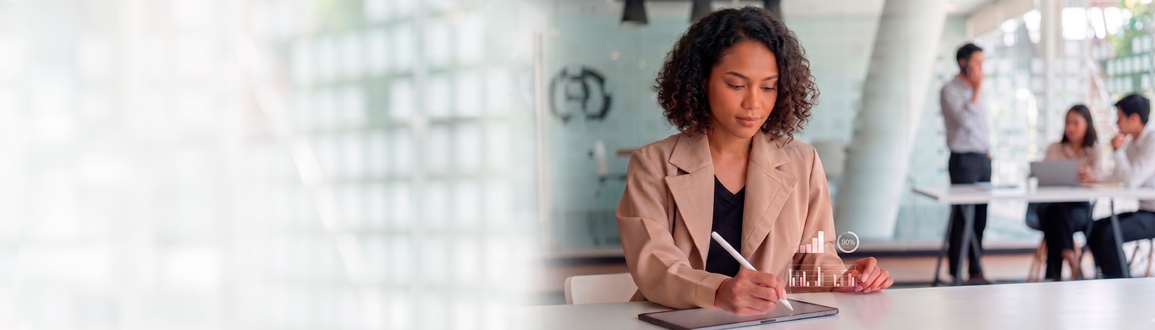 Mulher com blazer escreve em um tablet usando uma caneta com pequenos gráficos holográficos projetados sobre o aparelho. Ao fundo desfocado, três pessoas interagem em um escritório moderno e bem iluminado.